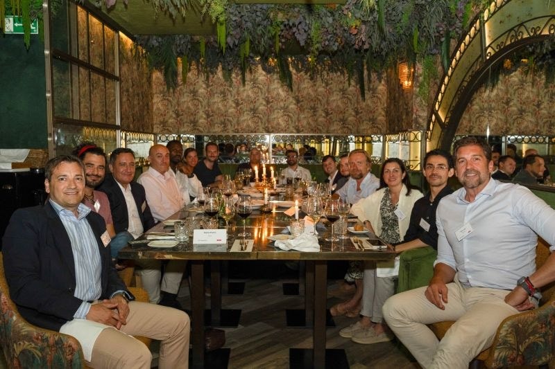 Guests seated along both sides of a candlelit dinner table.