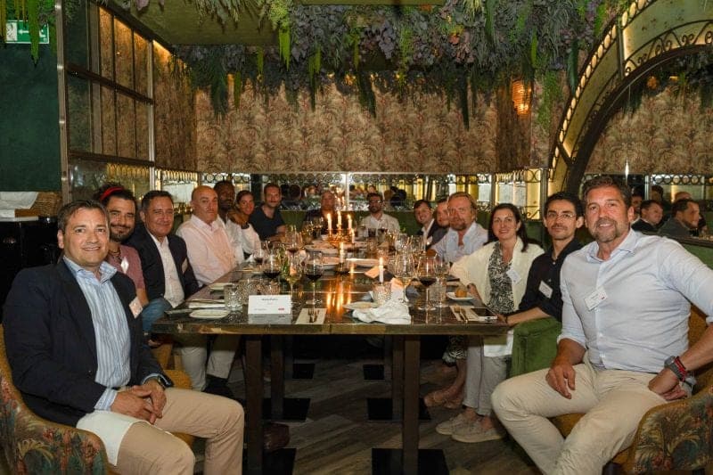 Guests seated along both sides of a candlelit dinner table.