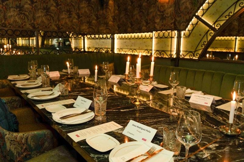 A candlelit dinner table set with place cards and glassware before guests arrive.